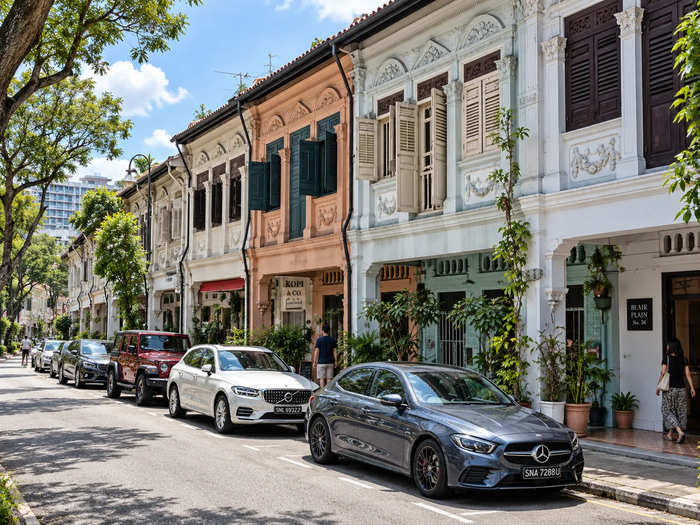 Terrace of conserved Blair Plain shophouses in cream, peach and pale blue, with shuttered upper windows and cars parked along the kerb