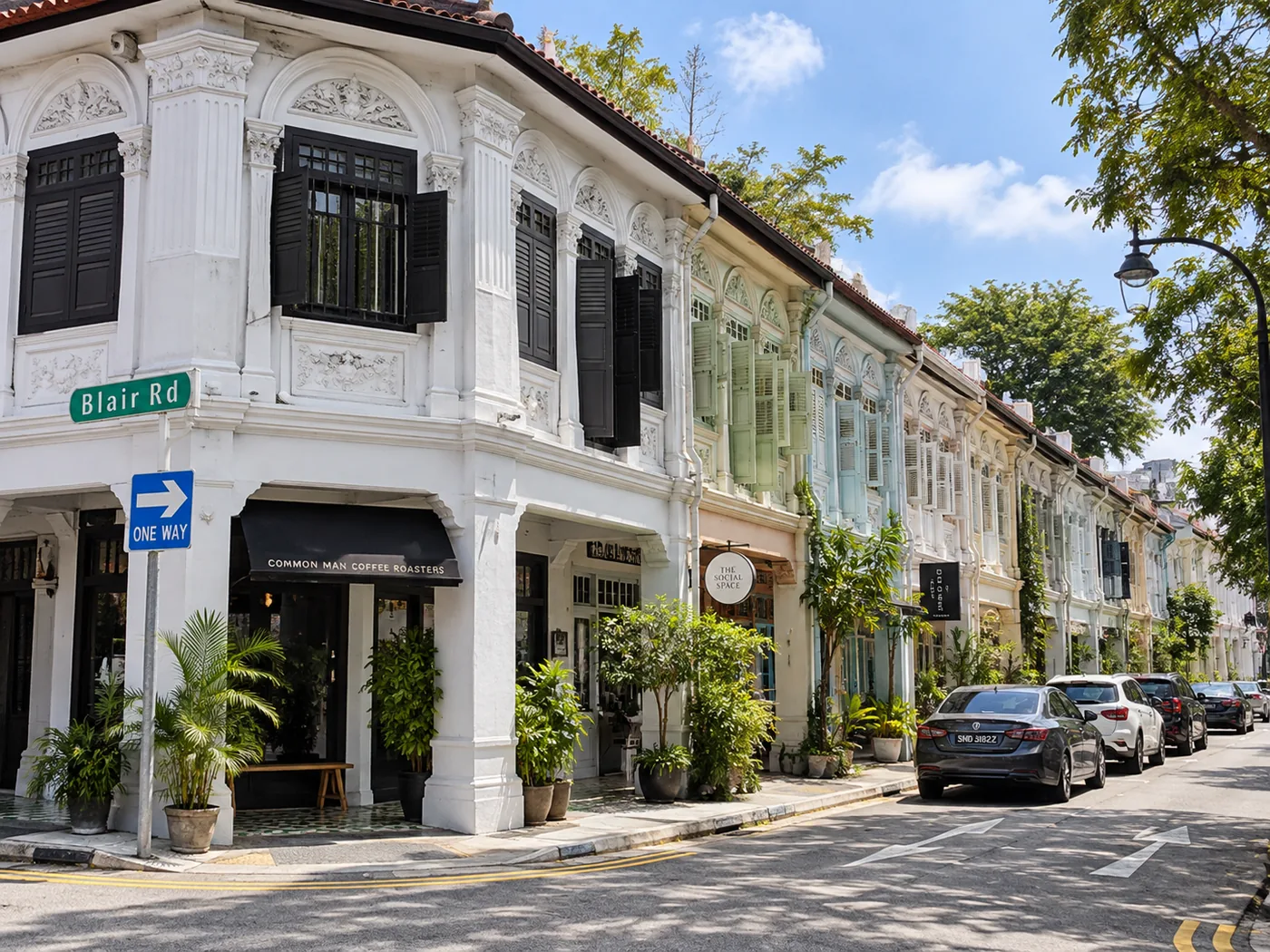 Corner shophouse on Blair Road with black timber shutters and moulded plasterwork, a row of pastel conserved shophouses running behind it