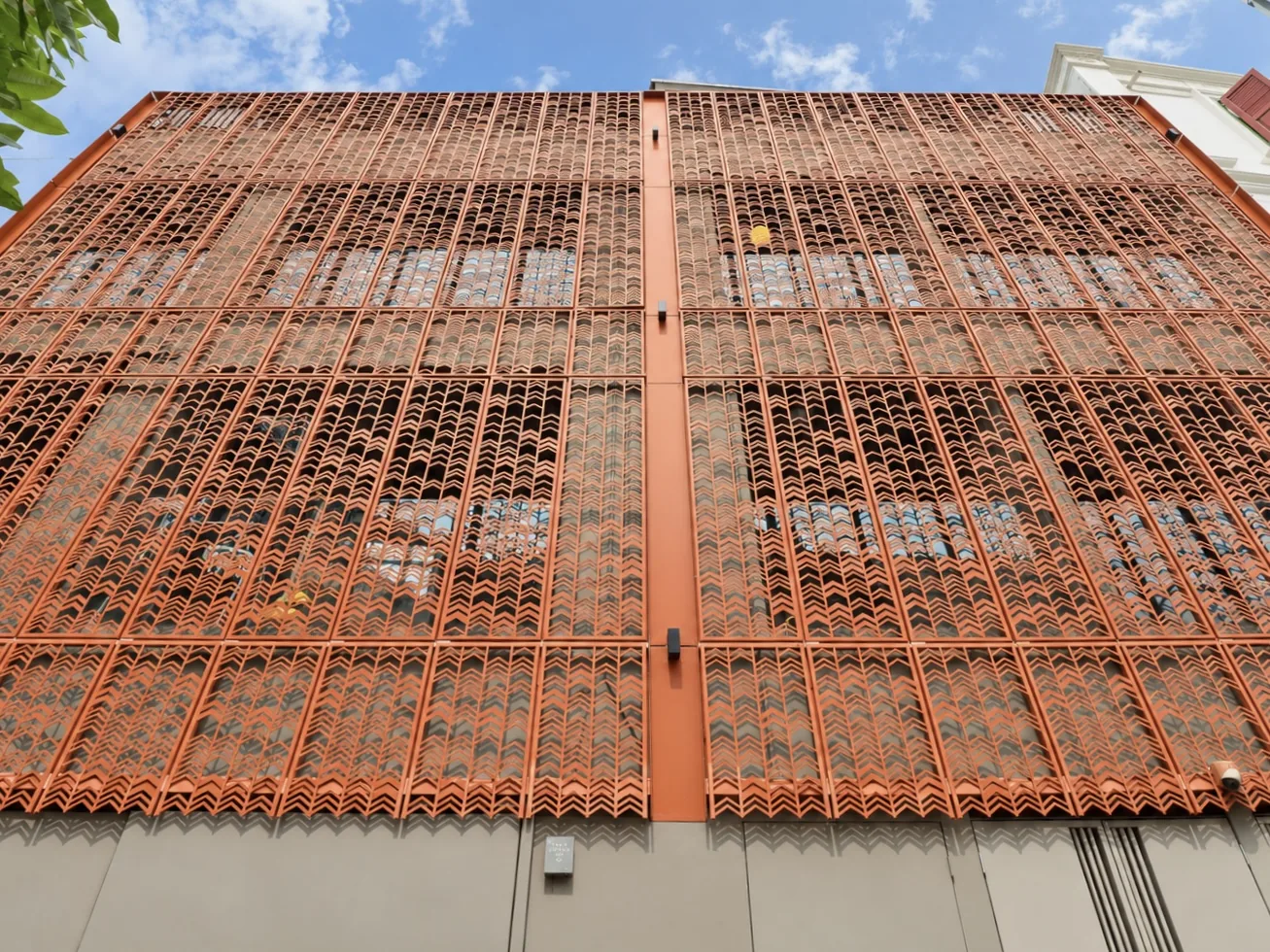 Perforated terracotta screen wall to the rear of the residential floors, seen from below against the sky