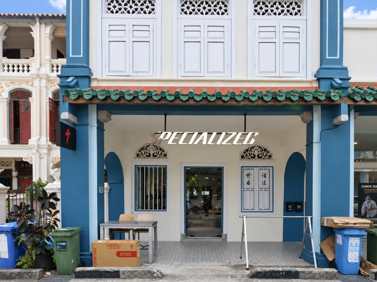 Commercial ground floor of No. 63: a bicycle shop behind teal columns and arched openings, with louvred shutters above