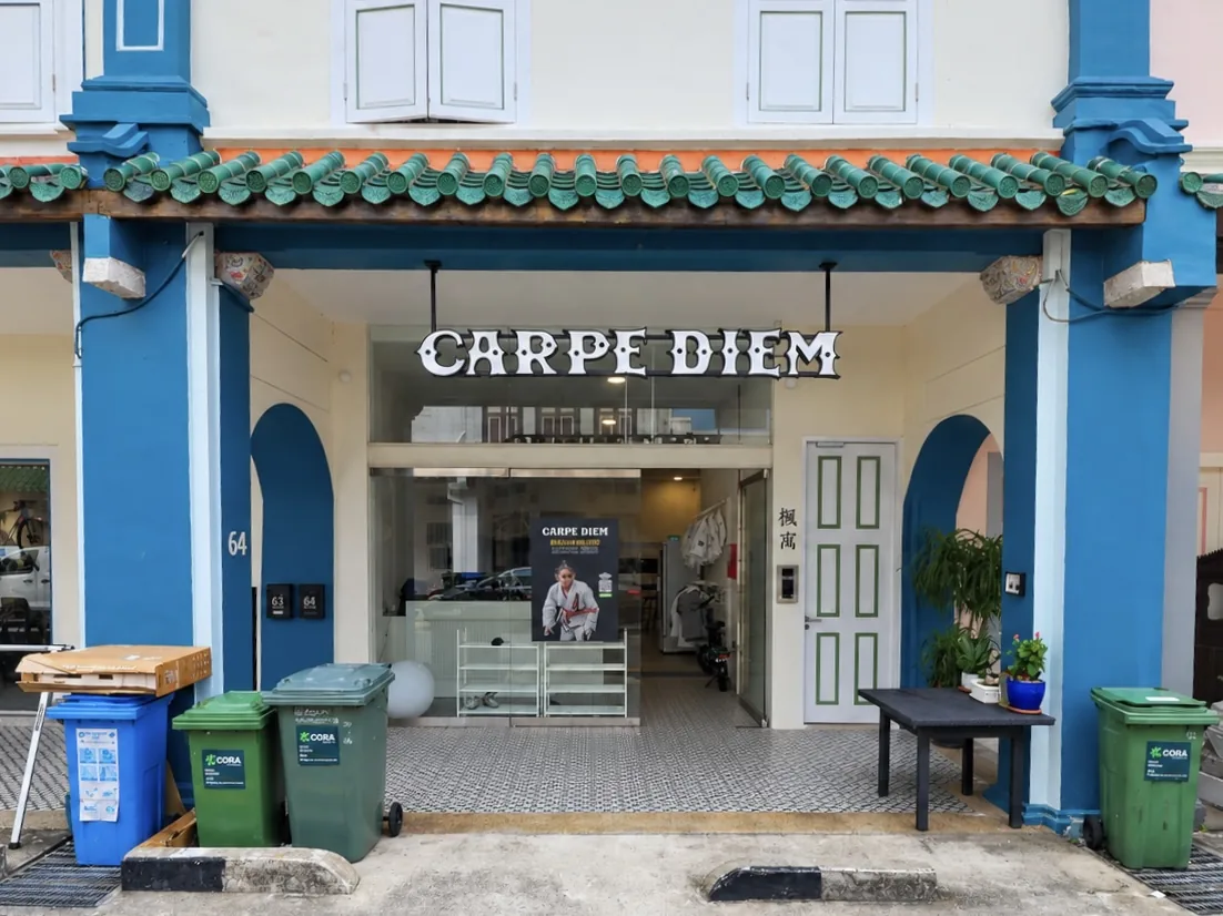 Commercial ground floor of No. 64: the Carpe Diem unit behind teal arched openings, with green pantile eaves above